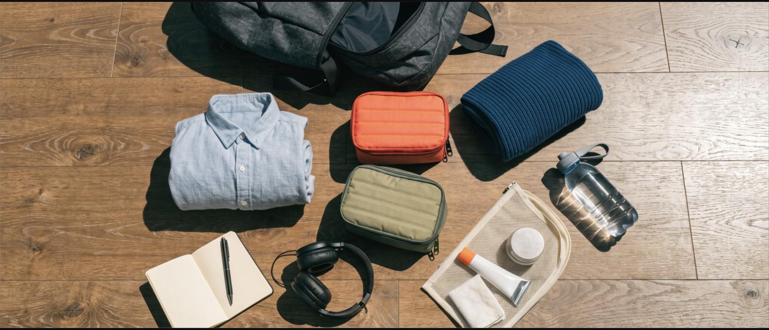 Contents of a travel backpack laid out on a wooden floor with packing cubes